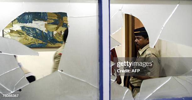 An Indian police officer is seen through the broken glass of the windows of the office of "Outlook" magazine in Mumbai, 14 August 2007, after it was...