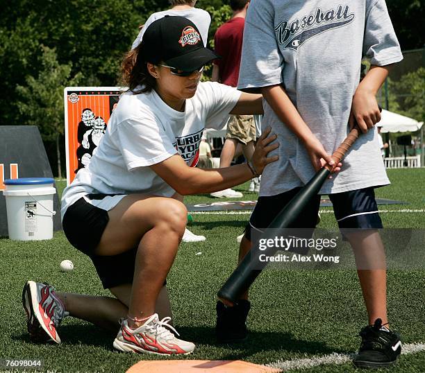 Chinese softball coach Zhang Xinyan of Shanghai practices training technique with a young U.S. Baseball player as Zhang participates in a coaching...