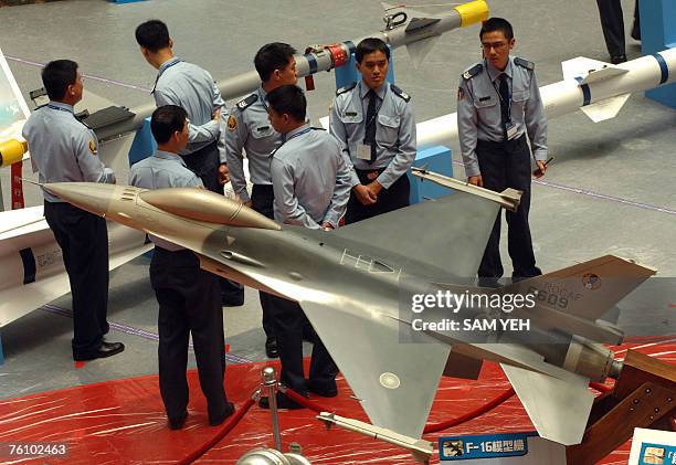 Taiwanese airforce officers stand behind a US-made F-16 fighter model during the aerospace and defense technology exhibition at the World Trade...