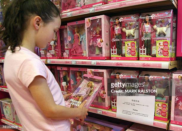 Young girl holds a Barbie doll next to a notice saying that the toy "Barbie and Tanner" made by US toy giant Mattel, which has just been recalled in...