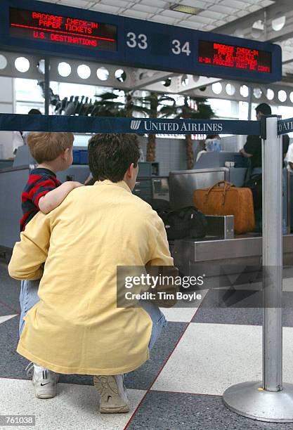 Kirsten Peachey from Chicago, who is traveling to Pittsburgh, and her two-year-old son Liam watch the goings-on at a ticket counter as they wait in...