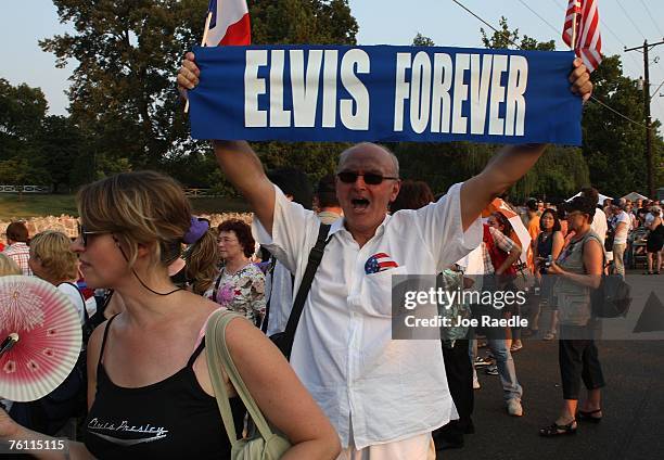 Orlando Bruno from Paris, France holds up a banner printed "Elvis Forever" as he stands in line during a vigil for the late Elvis Presley outside the...