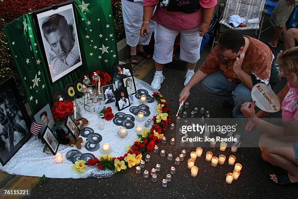 Stephen Galvin from Bryan, Texas lights candles arranged spell out "Elvis 30" beside Elvis Presley memorabilia during a vigil in memory of the late...