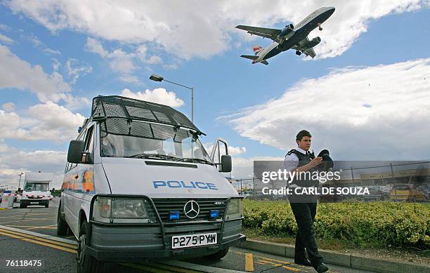 British police officer walks beside a police van near Heathrow airport's Terminal 3, in west London, 16 August 2007. Security has been increased...