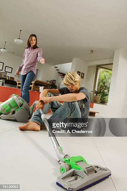 mother and son in living room, vacuum cleaner, indoors - vacuum cleaner woman stockfoto's en -beelden