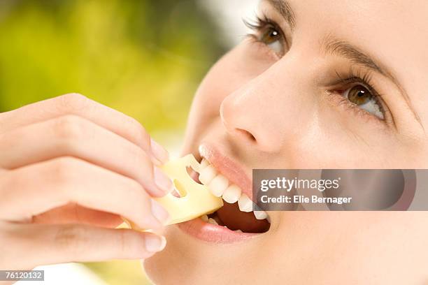 portrait of a young woman eating a piece of gruyere cheese, outdoors - eating cheese stockfoto's en -beelden