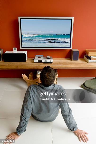 man watching tv sitting on floor - pantalla plasma fotografías e imágenes de stock