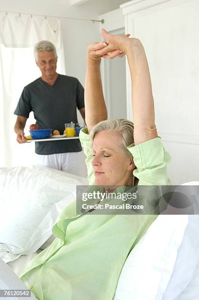 man bringing breakfast to woman stretching in bed - wellness kindness love stock pictures, royalty-free photos & images