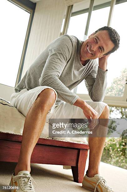 smiling man sitting on bed - short hair photos et images de collection