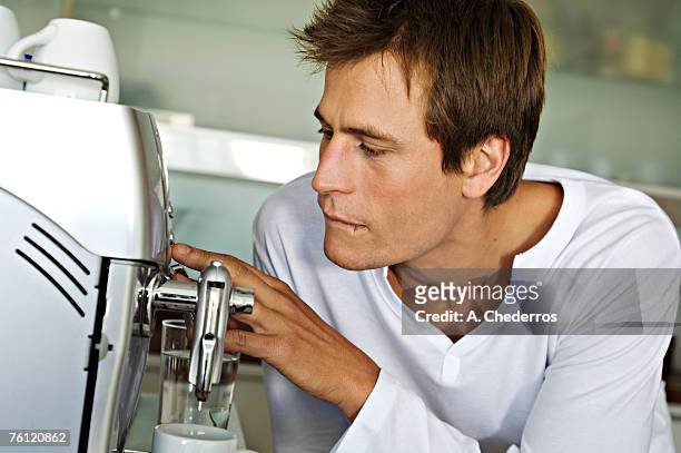 young man using espresso maker - espressomaschine stock-fotos und bilder