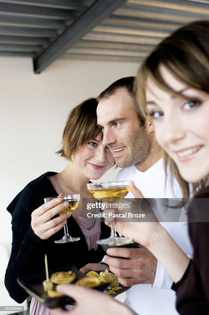 2 women and a man holding glasses of champagne