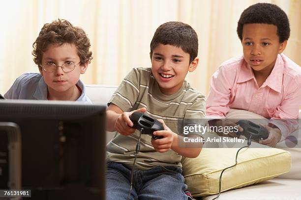 multi-ethnic boys playing video games - arab watching tv stock-fotos und bilder