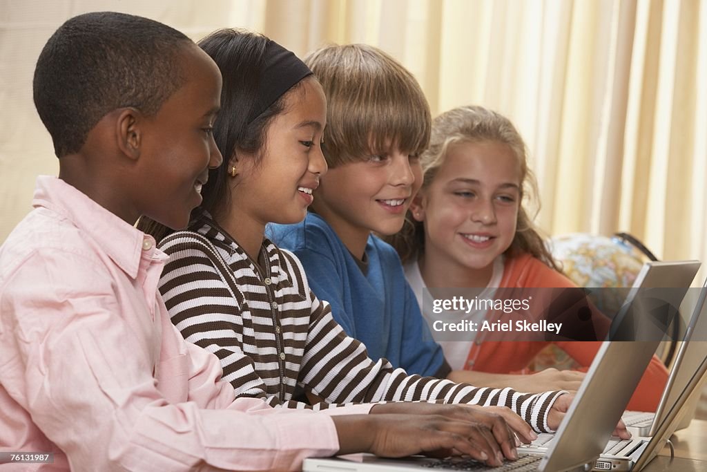 Multi-ethnic children typing on laptops