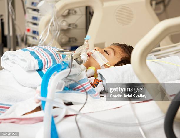 hispanic boy in intensive care unit bed - critical care stock-fotos und bilder