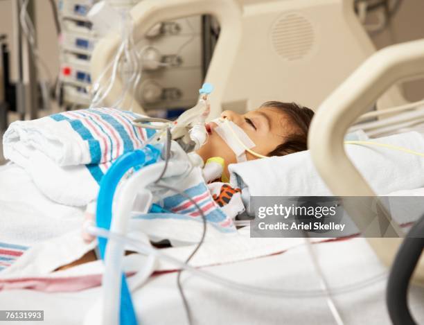 hispanic boy in intensive care unit bed - ventilador equipo respiratorio fotografías e imágenes de stock