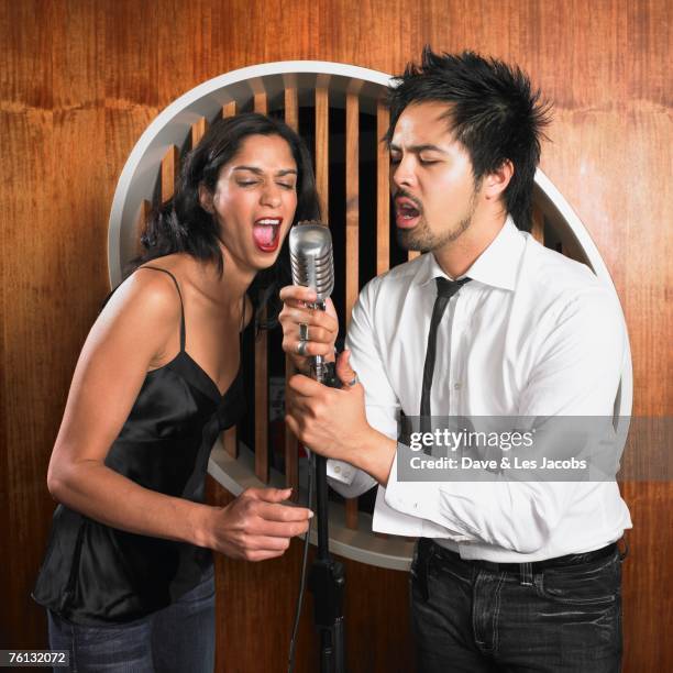 multi-ethnic couple singing into microphone - duet stock pictures, royalty-free photos & images