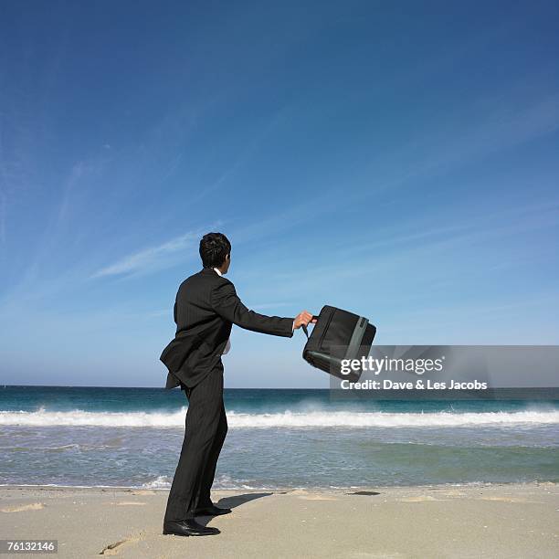 hispanic businessman throwing briefcase at beach - quitting job stock pictures, royalty-free photos & images