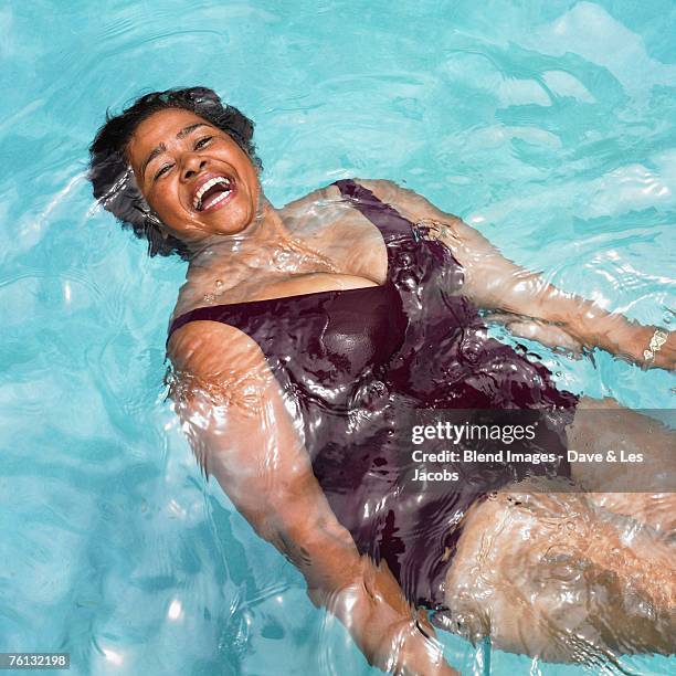 senior mixed race woman in swimming pool - mollige frau stock-fotos und bilder