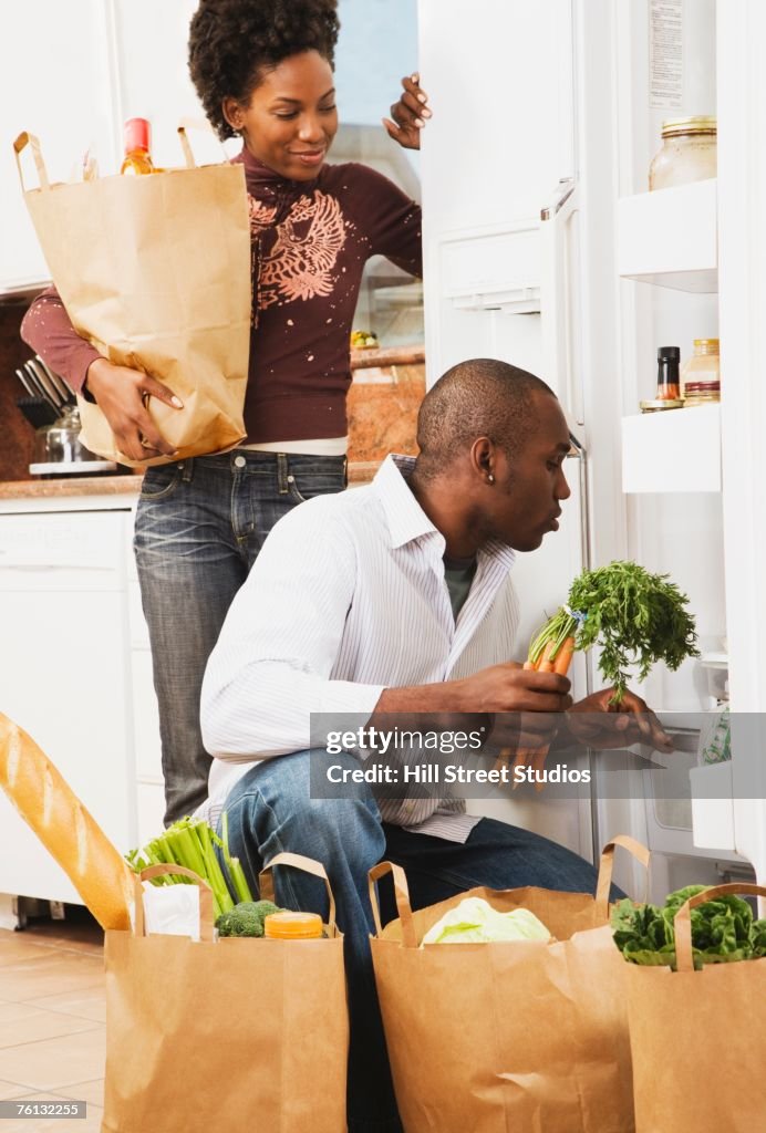 African American couple putting away groceries