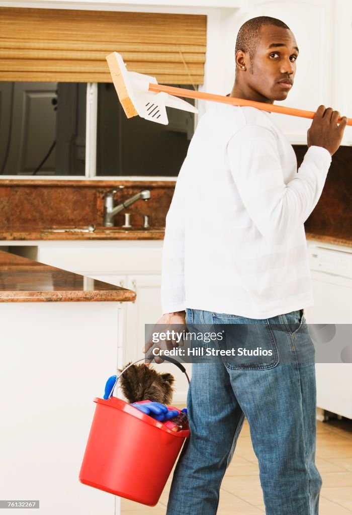 African American man carrying cleaning bucket and mop