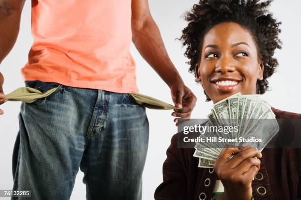 african american woman holding money next to man with empty pockets - empty pockets stock pictures, royalty-free photos & images