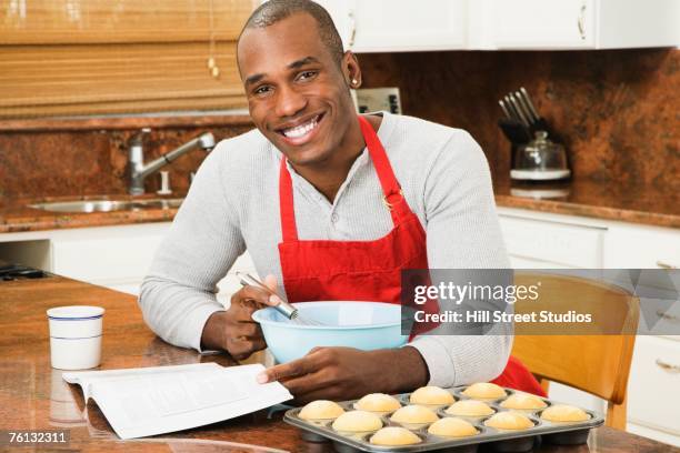 african american man baking with cookbook - black apron stock pictures, royalty-free photos & images