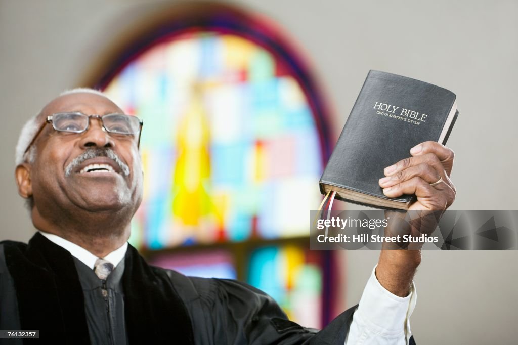 African American Reverend holding up Bible