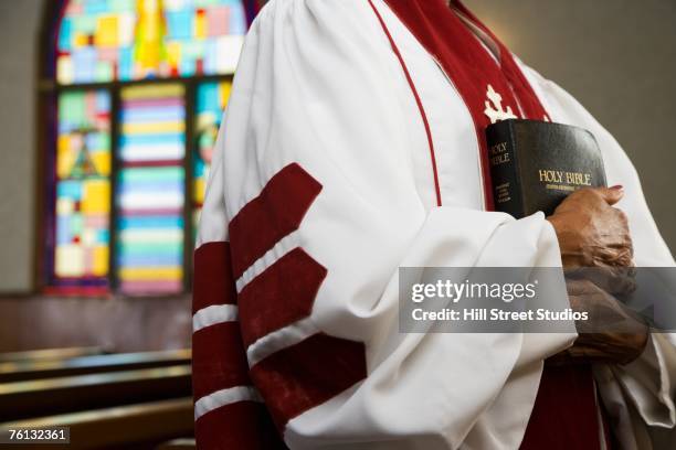 african american female reverend holding bible - geestelijken stockfoto's en -beelden