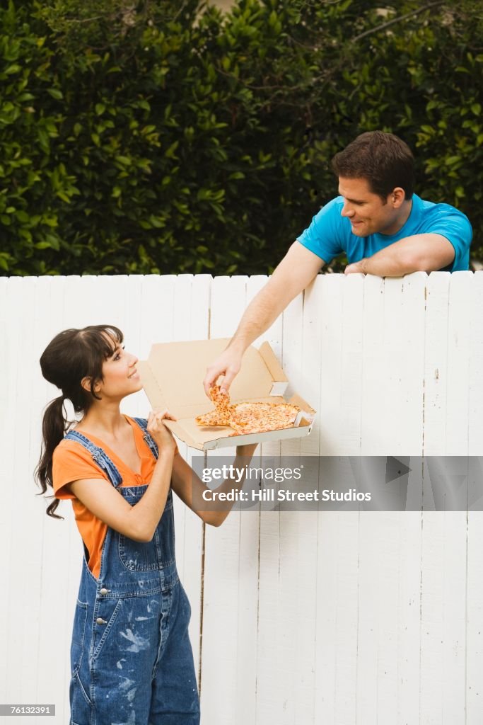 Multi-ethnic couple eating over newly painted fence