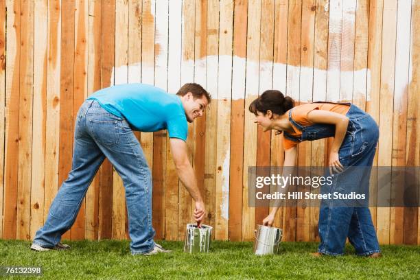 multi-ethnic couple painting fence - painting fence stock pictures, royalty-free photos & images