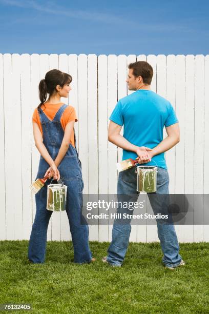 multi-ethnic couple painting fence - looking over fence stock pictures, royalty-free photos & images