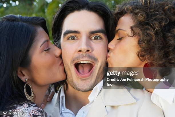 two women kissing man on cheek - cheek kiss stock pictures, royalty-free photos & images