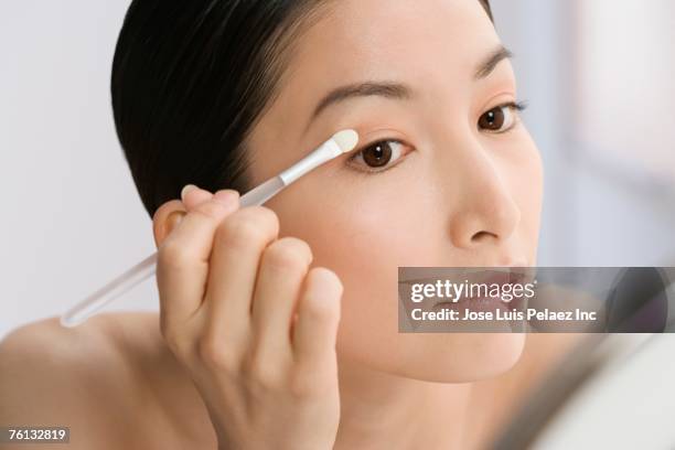 asian woman applying eye shadow - eyeshadow fotografías e imágenes de stock