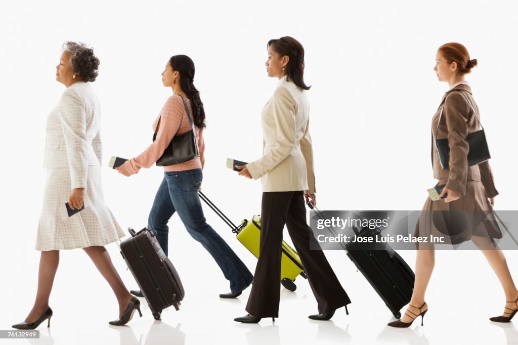 Multi-ethnic businesswomen pulling suitcases