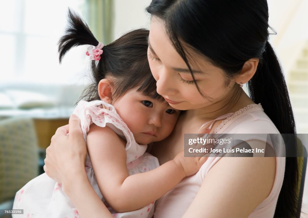 Asian mother hugging baby daughter