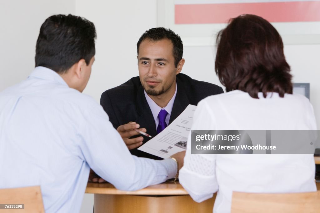 Hispanic couple making deal with car salesman