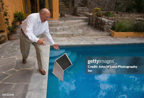senior man dropping laptop in swimming pool - misfortune stock pictures, royalty-free photos & images