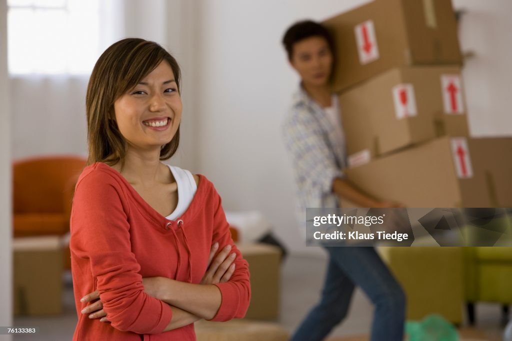 Asian woman laughing while husband carries boxes