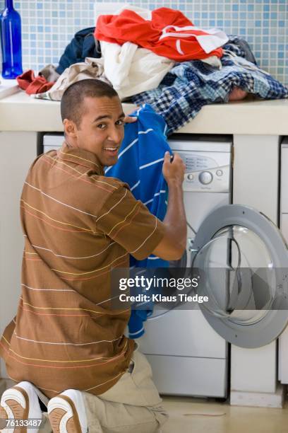young man doing laundry - gas washer dryer stock pictures, royalty-free photos & images