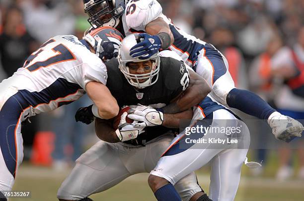 Oakland Raiders tight end Courtney Anderson is tackled by John Lynch, left, Nate Webster, top, and Nick Ferguson, bottom, at McAfee Coliseum in...