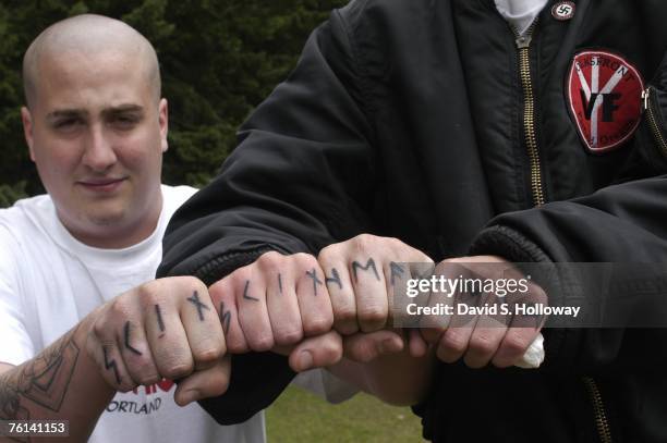 Jacob Laskey, left, and another skinhead member of Volksfront from Oregon show off their tattoos while attending the 2003 Aryan Nations World...