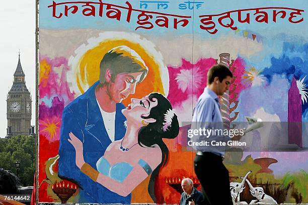 Commuters pass a giant painting of a Bollywood film poster in Trafalgar Square before heading to work on August 17, 2007 in London, England. The...