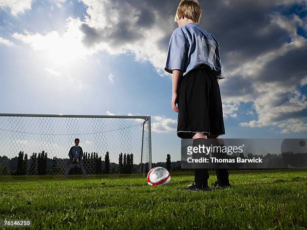 boys (10-11, 12-13) playing football on pitch, rear view, low angle - shootout stock pictures, royalty-free photos & images