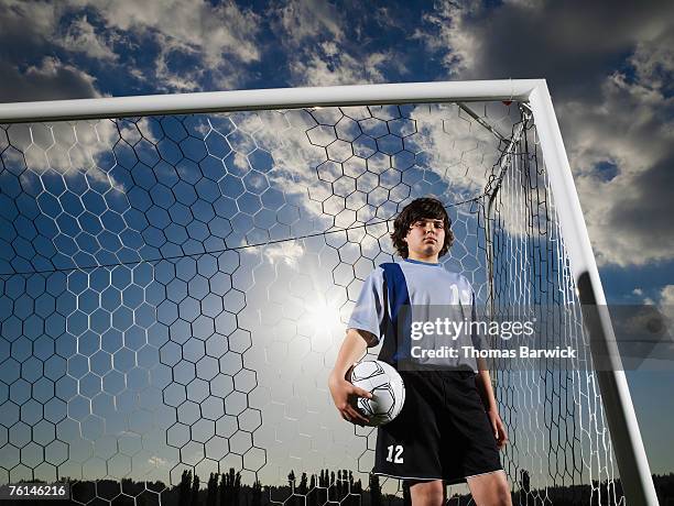 boy (10-11) as goalkeeper,standing in goal holding football,low angle - boy goalie standing in front of goal net stock pictures, royalty-free photos & images