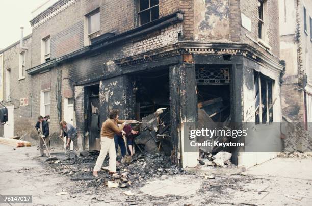 Workers clearing debris from a burnt-out welding shop in Railton Road, Brixton, south London, after the first Brixton riot, 13th April 1981.