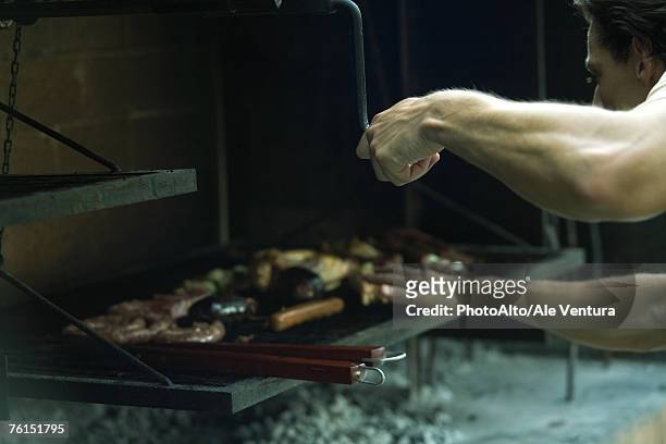 man grilling meat on barbecue - bending stock pictures, royalty-free photos & images