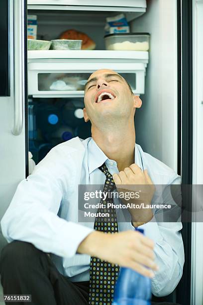 "man sitting in front of open refrigerator, pulling on collar, head back" - funny fridge foto e immagini stock