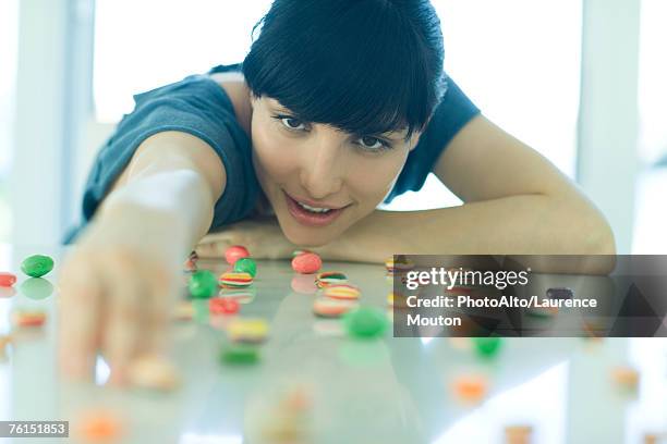 "table spread with candy, woman resting head on arms, reaching for piece of candy" - head on table stock-fotos und bilder