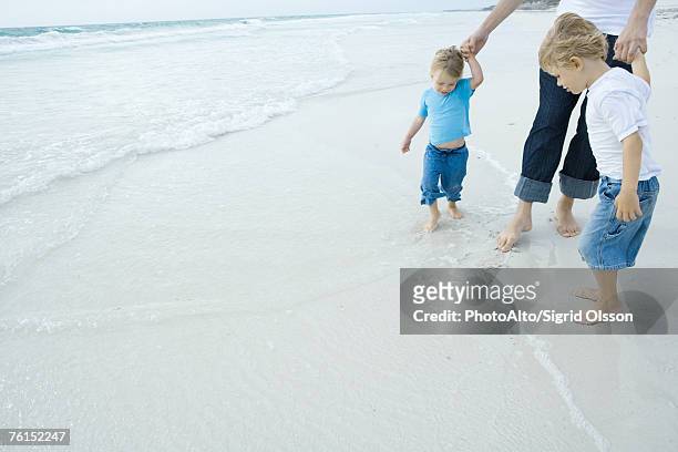 father and children walking in surf - teen boy shorts stockfoto's en -beelden