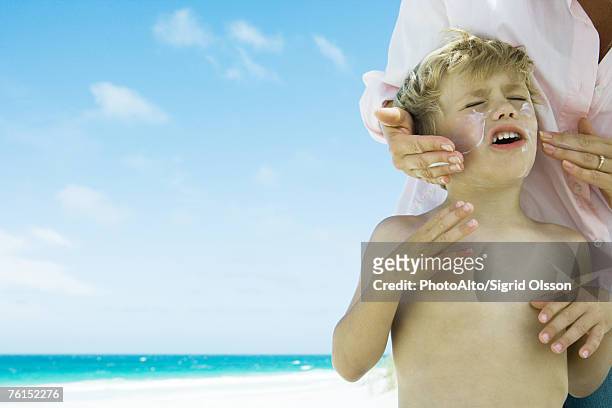 mother putting sunscreen on child at beach - putting lotion stock pictures, royalty-free photos & images